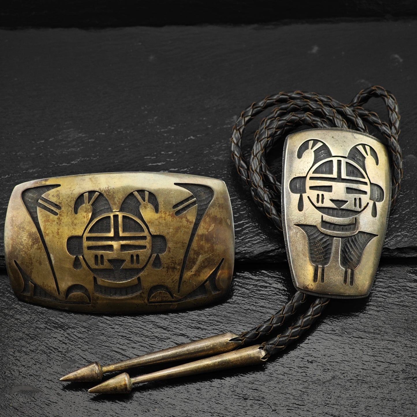 Sterling Silver belt buckle and bolo tie on a dark textured surface