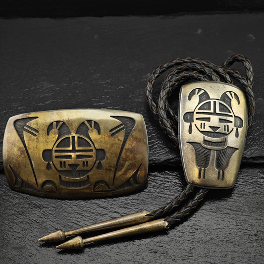 Sterling Silver belt buckle and bolo tie on a dark textured surface