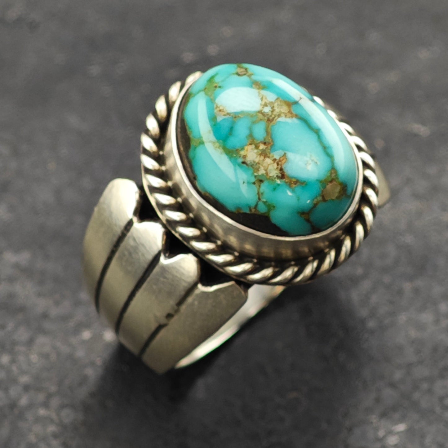 Turquoise stone ring with silver band on a dark gray background